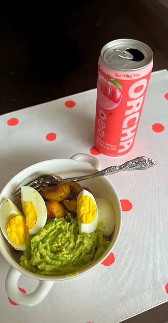 A Peach Oolong can beside a breakfast bowl of eggs, avocado and potatoes