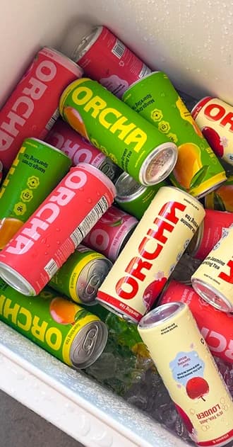 A cooler packed with iced Orcha cans in all three flavors